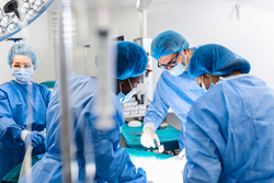 Diverse Team of Professional surgeon, Assistants and Nurses Performing Invasive Surgery on a Patient in the Hospital Operating Room. Surgeons Talk and Use Instruments. Real Modern Hospital.