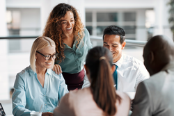 Smiling group of diverse businesspeople working together around a meeting table in an office complex lobby